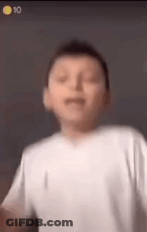 A Young Boy In A White Shirt Is Making A Funny Face And Dancing . GIF