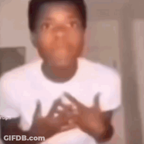 A Young Boy In A White Shirt Is Making A Funny Face While Holding His Hands To His Chest . GIF