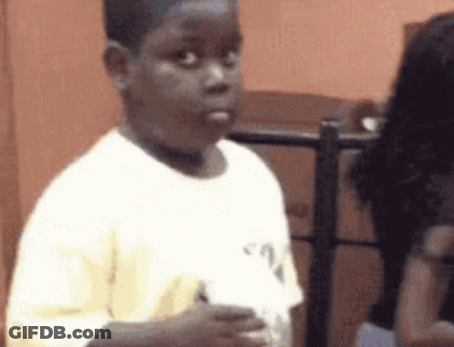 A Young Boy In A White Shirt Is Standing In Front Of A Woman . GIF