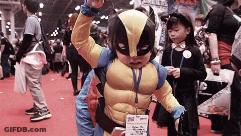 A Young Boy In A Wolverine Costume Is Standing In A Crowd . GIF