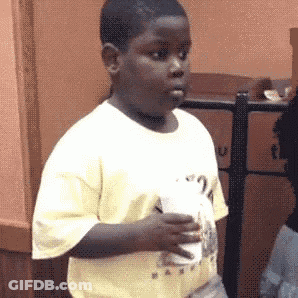 A Young Boy In A Yellow Shirt Is Holding A Cup Of Coffee . GIF
