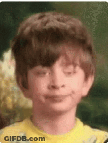 A Young Boy In A Yellow Shirt Is Smiling With His Eyes Closed . GIF