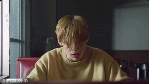 A Young Boy In A Yellow Sweater Sits At A Table GIF
