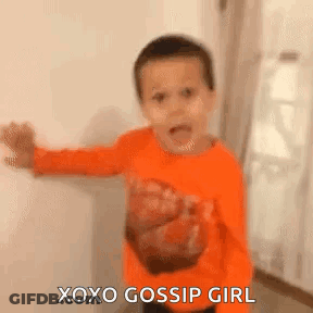 A Young Boy In An Orange Shirt Is Standing In Front Of A White Wall And Says `` Xoxo Gossip Girl '' . GIF