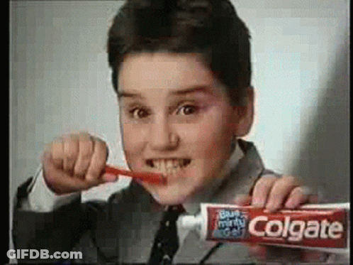 A Young Boy Is Brushing His Teeth With A Tube Of Colgate Toothpaste . GIF