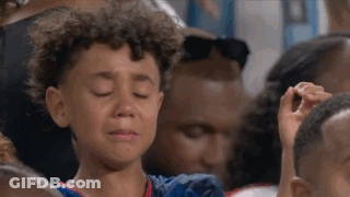 A Young Boy Is Crying In A Crowd Of People At A Sports Game . GIF