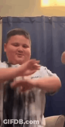 A Young Boy Is Dancing In A Living Room While Sitting On A Couch . GIF