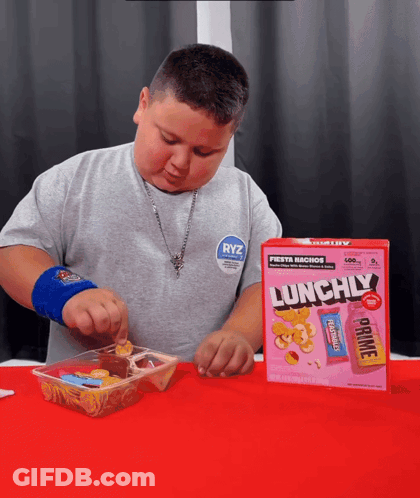 A Young Boy Is Eating A Box Of Lunchily Cereal GIF