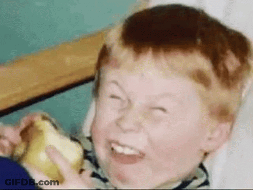 A Young Boy Is Eating An Apple And Making A Funny Face . GIF