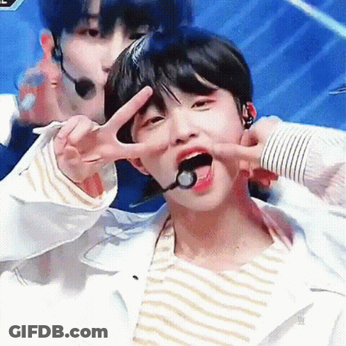 A Young Boy Is Giving A Peace Sign With His Tongue Out . GIF