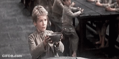 A Young Boy Is Holding A Bowl With A Spoon In It . GIF