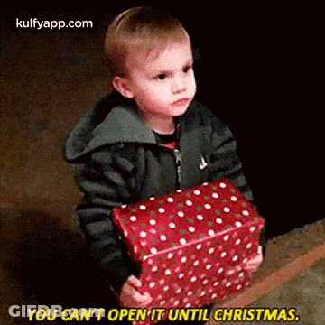 A Young Boy Is Holding A Christmas Present And Saying `` You Can 'T Open It Until Christmas '' . GIF