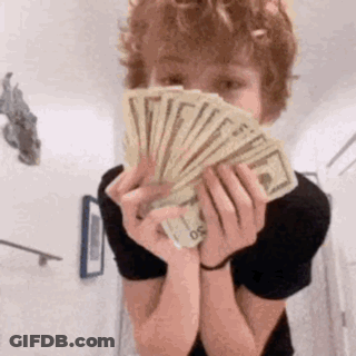 A Young Boy Is Holding A Fan Of Money In Front Of His Face . GIF