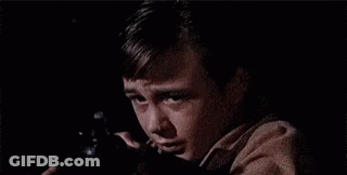 A Young Boy Is Holding A Gun In His Hand And Crying In The Dark . GIF