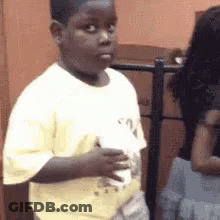 A Young Boy Is Holding A Piece Of Paper In His Hand . GIF