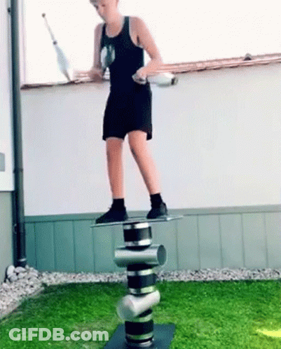 A Young Boy Is Juggling Balls While Standing On A Stack Of Cylinders . GIF