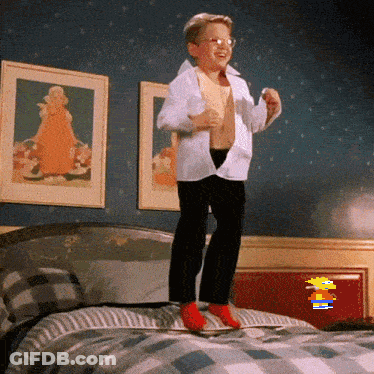 A Young Boy Is Jumping On Top Of A Bed With A Cartoon Character In The Background GIF