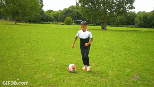 A Young Boy Is Kicking A Soccer Ball On A Field GIF