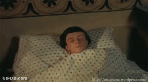 A Young Boy Is Laying In Bed With His Eyes Closed GIF