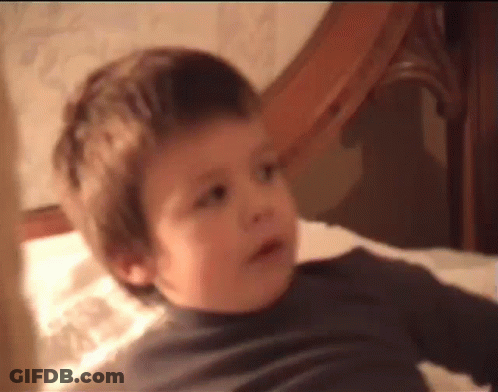 A Young Boy Is Laying On A Bed And Making A Face . GIF
