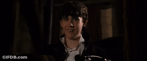 A Young Boy Is Laying On A Bed In The Dark . GIF