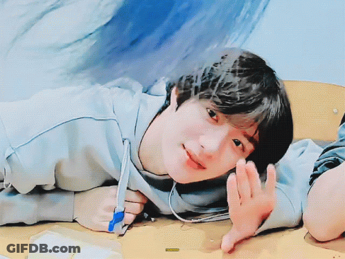 A Young Boy Is Laying On A Table With A Pen In His Hand And A Sticker That Says ' A ' On It GIF