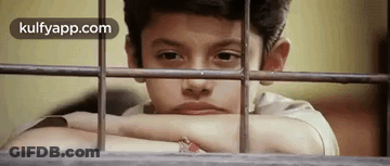 A Young Boy Is Looking Out Of A Window With His Head Resting On A Railing . GIF
