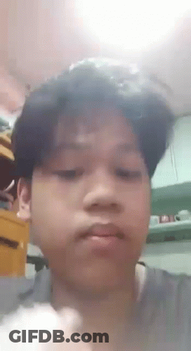 A Young Boy Is Making A Funny Face In A Kitchen While Holding A Piece Of Food . GIF