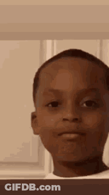 A Young Boy Is Making A Funny Face In A Room . GIF