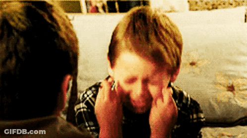 A Young Boy Is Making A Funny Face While Sitting On A Couch With A Man . GIF