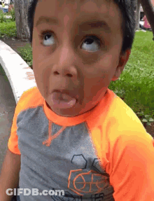 A Young Boy Is Making A Funny Face With His Tongue Out . GIF