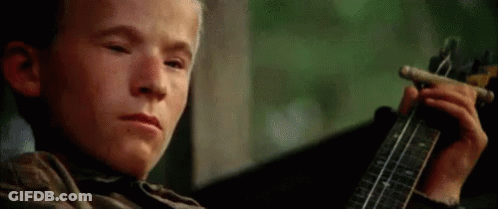A Young Boy Is Playing A Guitar While Smoking A Cigar . GIF