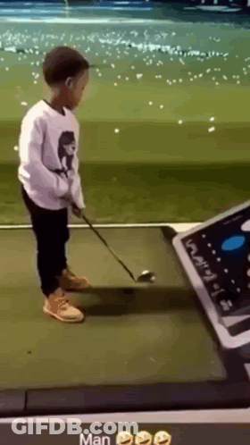 A Young Boy Is Playing Golf On A Driving Range GIF