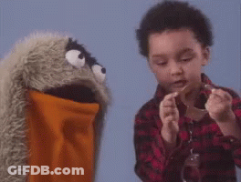 A Young Boy Is Playing With A Puppet While Holding A Piece Of Paper . GIF
