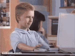 A Young Boy Is Sitting At A Desk In Front Of A Laptop Computer GIF