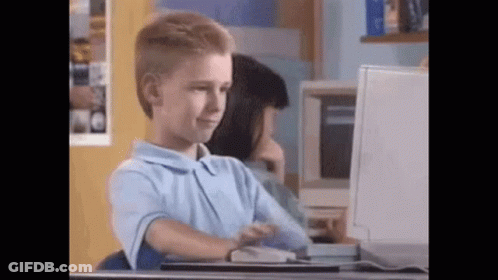 A Young Boy Is Sitting At A Desk Looking At A Computer Screen . GIF