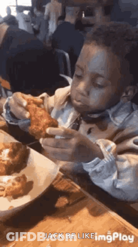 A Young Boy Is Sitting At A Table Eating Fried Chicken With A Fork . GIF