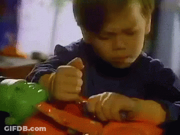 A Young Boy Is Sitting At A Table Playing With A Toy Dinosaur . GIF