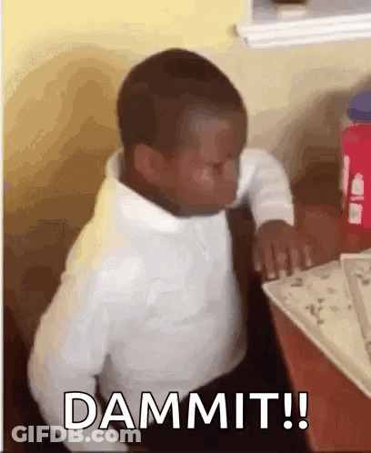 A Young Boy Is Sitting At A Table With His Eyes Closed And The Word Dammit Written On The Screen . GIF