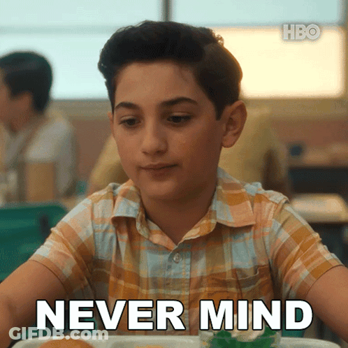 A Young Boy Is Sitting At A Table With The Words Never Mind Written On His Face GIF