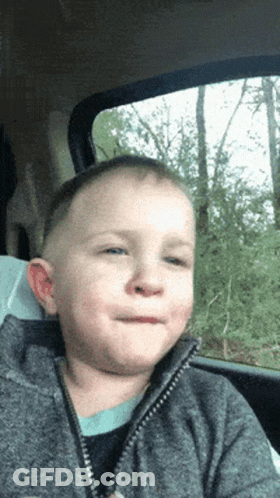 A Young Boy Is Sitting In A Car With His Mouth Open GIF