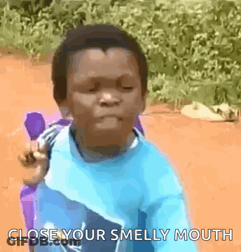 A Young Boy Is Sitting In A Chair And Making A Funny Face With The Words Close Your Smelly Mouth . GIF