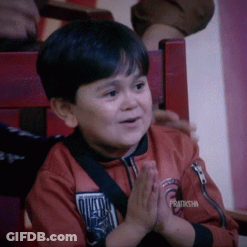 A Young Boy Is Sitting In A Chair With His Hands Folded And The Words Pratiksha On The Bottom GIF