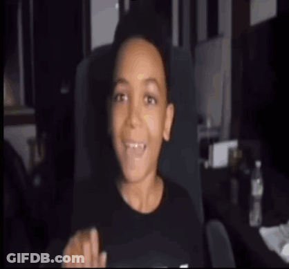 A Young Boy Is Sitting In A Chair With His Mouth Open And Pointing . GIF