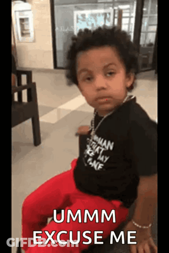 A Young Boy Is Sitting In A Chair With The Words Ummm Excuse Me Written On The Screen . GIF