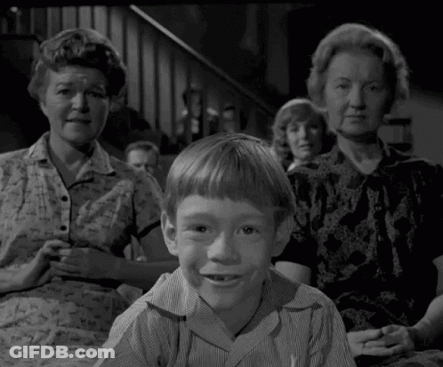 A Young Boy Is Sitting In Front Of A Group Of People . GIF