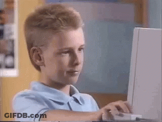 A Young Boy Is Sitting In Front Of A Laptop Computer . GIF