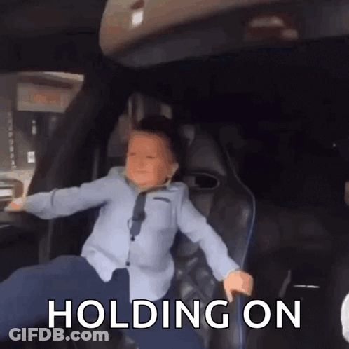 A Young Boy Is Sitting In The Back Seat Of A Car With The Words " Holding On " Above Him GIF