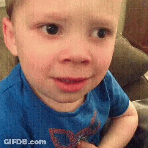 A Young Boy Is Sitting On A Couch Making A Funny Face . GIF