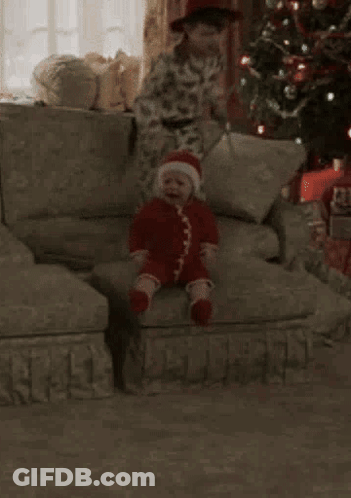 A Young Boy Is Sitting On A Couch Next To A Stuffed Monkey . GIF